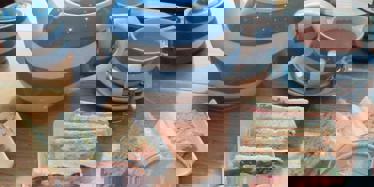 blue and white stripy tea pot, cup of tea and selection of finger sandwiches